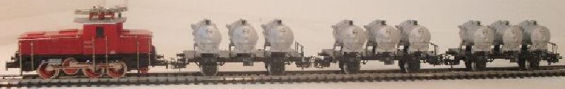 analog Artikel NEU, im original Karton verpackt. Elektrische Lokomotive E 63 der DB, Aufschrift E 63 04. 3 Stück Behältertragwagen mit silbernen Behältern der EVA. Wagennr. 012220, 012225, 012230.
